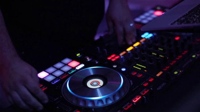 Dj play mix music turntable deck with colors light hands close up slow motion. Finger turn knobs press pads on midi controller grid professional mixer function console launchpad search track in laptop