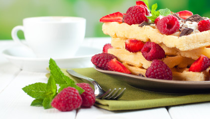 Breakfast with belgian waffles covered with raspberry and strawberry