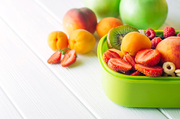 Lunch box with fruits, berries and crunches on white wooden background © lithiumphoto