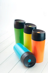 Thermos mugs on the white wooden table on white background