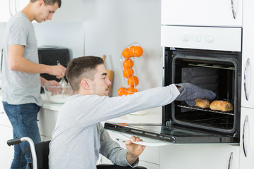 disabled young man in wheelchair opens the oven
