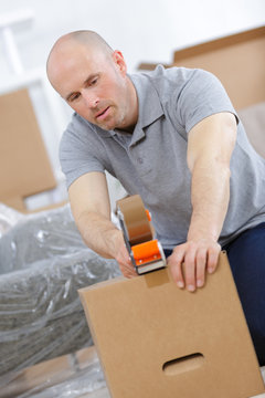 Man Packing Things And Taping Boxes