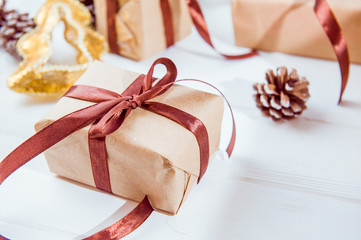 Christmas holidays composition with gifts in craft paper with satin ribbon on the white wooden background with copy space for your text. Selective focus