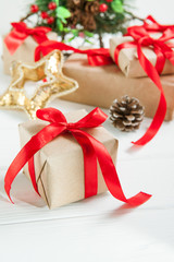 Christmas holidays composition with gifts in craft paper with red satin ribbon on the white wooden background with copy space for your text. Selective focus
