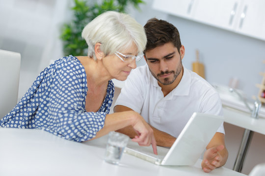 young man helping elderly woman surfing on the web