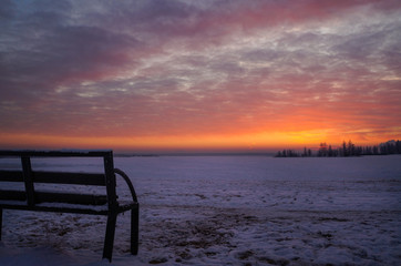 Fototapeta na wymiar The red color of the sunset. Winter red sunset. Bench at sunset.