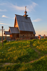 Wooden orthodox temple in the rays of sunset/A wooden orthodox church stands on a hill. The church is illuminated by the rays of the sun, which goes beyond the horizon.Plyos, the Golden ring of Russia