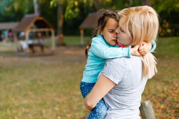 mother holding her crying daughter in arms