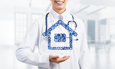 Symbol of homepage or accomodation made with cogwheels presented in female palms