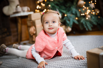 child little girl with gift box near christmas tree and fireplace at home