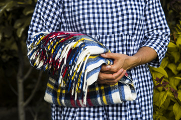 multi-colored plaid in the hands of a woman in a blue checkered dress. autumn concept