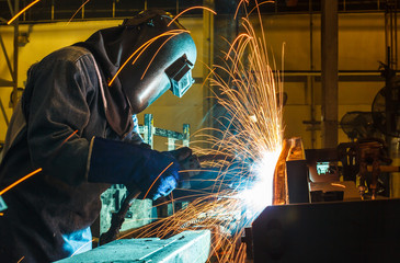 Worker, welding in a car factory with sparks, manufacturing, industry
