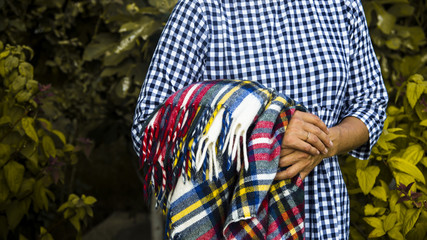 multi-colored plaid in the hands of a woman in a blue checkered dress. autumn concept