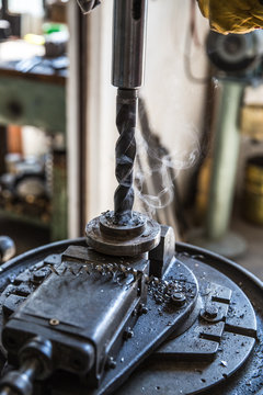 Drill close up - Close up drill tool in chuck during metal cutting process hole boring in iron piece at industrial factory workshop