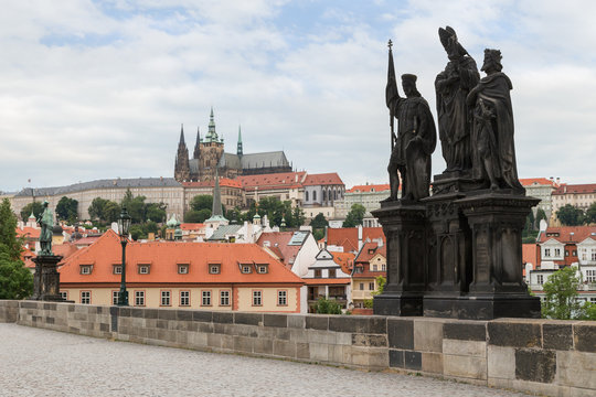 View of Prague Castle and other buildings at the Mala Strana district and statue of Saints Norbert of Xanten, Wenceslas and Sigismund on the north side of the Charles Bridge (Karluv most) in Prague.