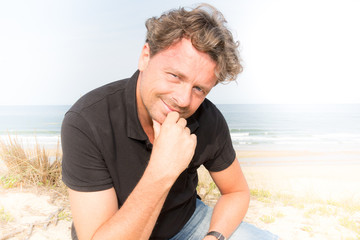 cheerful man tourist sitting in touristic beach