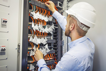 Service engineer in data center. Engineer in white helmet performs connection of optical fiber...