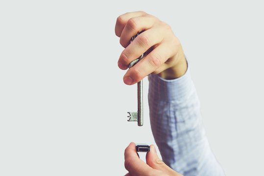Man holds a key in his hand and tries to open memory card. Cyber security and data security on the memory card against hacking. Isolated, white background.