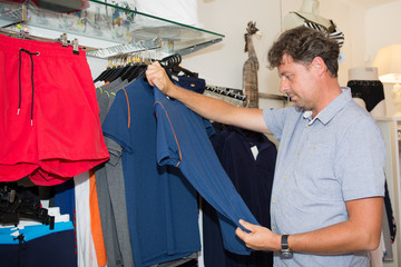 handsome smiling man working with clothes in boutique