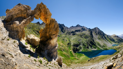 The famous Arc de Tortisse, natural arch in the national park of Mercantour (France) with the upper lake of Vens on the background