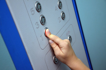 Child finger press button in elevator.