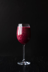 A great glass of banana-berry juice on a black background