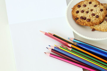 back to school: school supplies, isolated pencils, pens, notepad and chocolate chip cookies