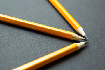 Three yellow pencils on a black background, concept.