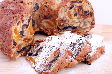 isolated traditional christmas stollen cake, sweet german bread, with dried fruits on wooden background