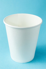 Takeaway white coffee drinking paper cup for hot tea, coffee and juice isolated on blue background, mockup.