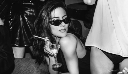 Posh female with glass of champagne and cigarettes on party.