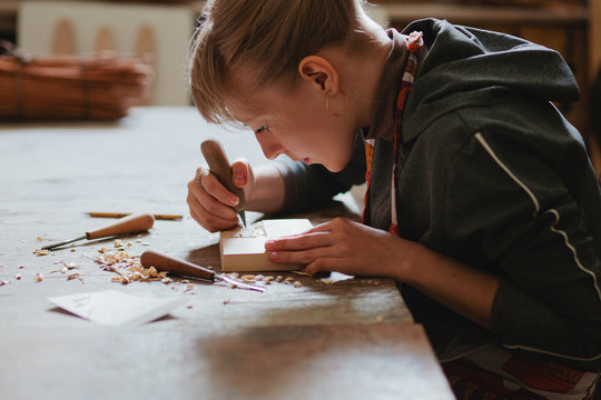 Woman carpenter carves a wooden stamp