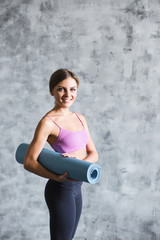 Portrait smiling fitness woman holding yoga mat.