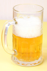 glass of fresh light beer, lager on yellow background