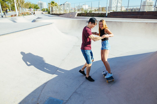 Teenage couple having fun in a skate park in summer.