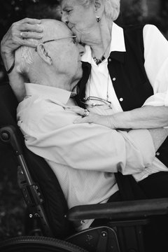 Tender Moment Between Senior Couple Outside Together With Wheelchair