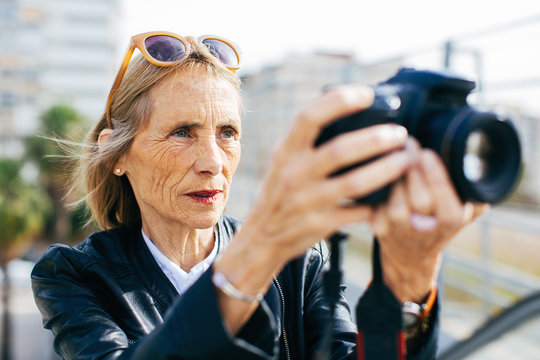 Mature woman taking photos with her camera in the city.