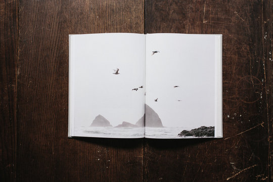 book of coast inspired photographs open on wood table