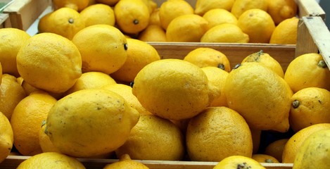 Fresh lemons for sale on wooden boxes on a market stall