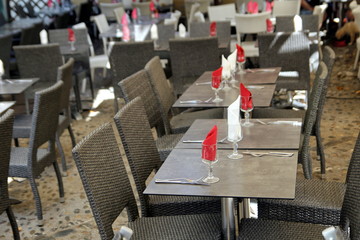 Empty tables set with red and white napkins at an outside restaurant