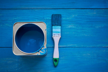 Bank of blue paint and brush on a wooden background