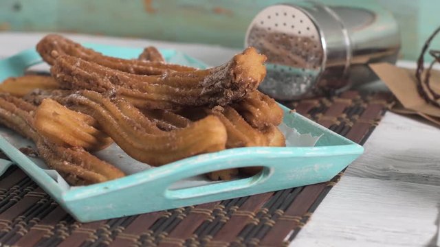 Traditional churros with hot chocolate dipping sauce on wooden counter top.