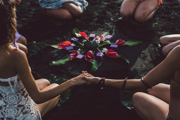 Women on the beach join hands around the flower mandala