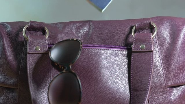 4k Travel concept with woman putting passport into carry bag with sunglasses, closeup.