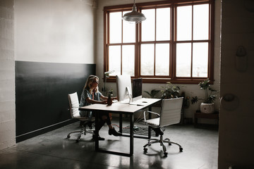 young person working at desk on computer in bright office