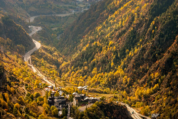 Main highway in Andorra bends and turns, near the Meritxell chapel, through a valley, at the peak of fall foliage colors - obrazy, fototapety, plakaty
