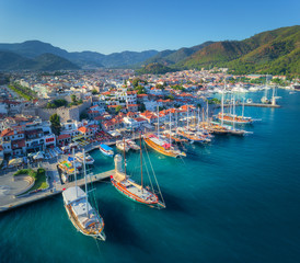 Aerial view of boats and beautiful architecture at sunset in Marmaris, Turkey. Colorful landscape with boats in marina bay, sea, city, mountains. Top view from drone of harbor with yacht and sailboat