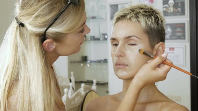 Makeup Specialist artist makes a blonde woman model beautiful Gentle makeup before an important event. step by step