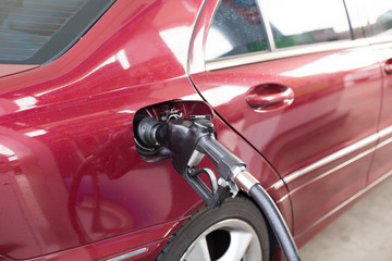 Fuel nozzle adding gasoline to a car at gas station