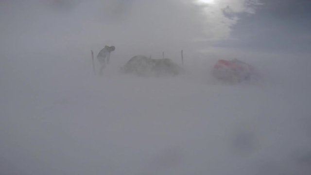 A shot of a powerful blizzard. The man is outside his tent while the blizzard is occurring.